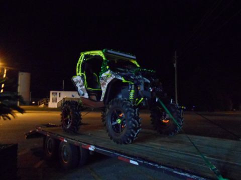 1992 Ford Bronco - A custom off-road vehicle, modified with neon green accents and large tires, is transported on a flatbed trailer after dark.