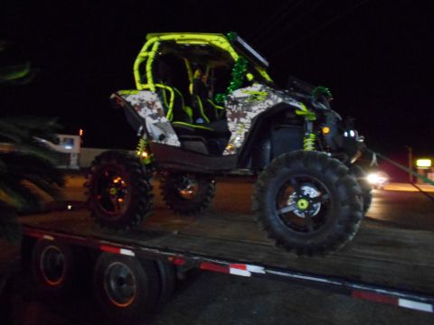 1992 Ford Bronco - Off-road side-by-side vehicle with custom paint and roll cage loaded onto a trailer.