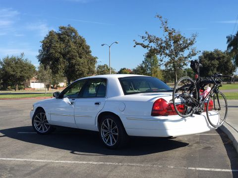 1989 Mazda MX-6 - A white sedan is parked in a lot with a bicycle mounted on a rack on its trunk.