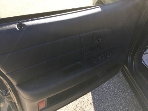 2001 Ford Crown Victoria - Close-up of a car's interior door panel, showing the window controls and door handle.