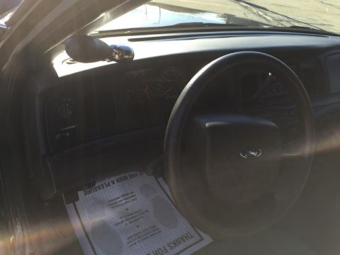 2001 Ford Crown Victoria - Interior view of a 2001 Ford Crown Victoria, showing the steering wheel, dashboard, and a floor mat with text.