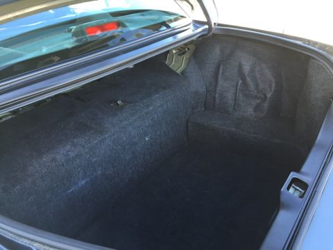 2001 Ford Crown Victoria - The spacious trunk of a sedan is shown, with dark carpeting and a visible latch mechanism.