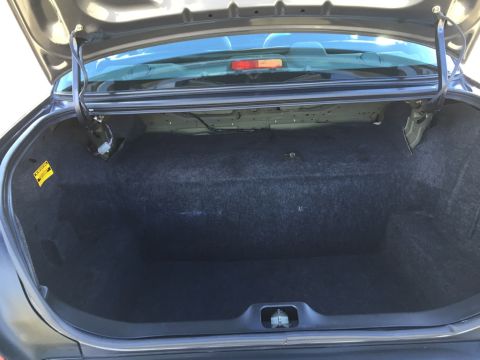 2001 Ford Crown Victoria - The interior of an empty car trunk shows the carpeted space and trunk lid hinges.