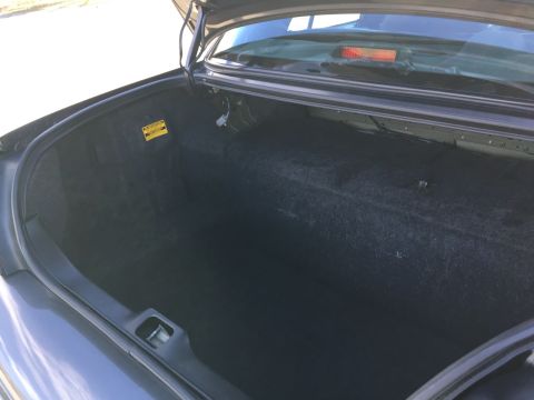 2001 Ford Crown Victoria - The trunk of the car is empty, showing the carpet lining and a yellow warning sticker.
