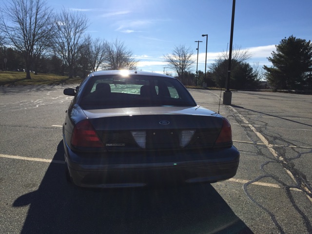 Rear view of a dark sedan with brake lights on in a parking lot.
