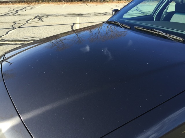 Dark gray car hood with reflections and white specks