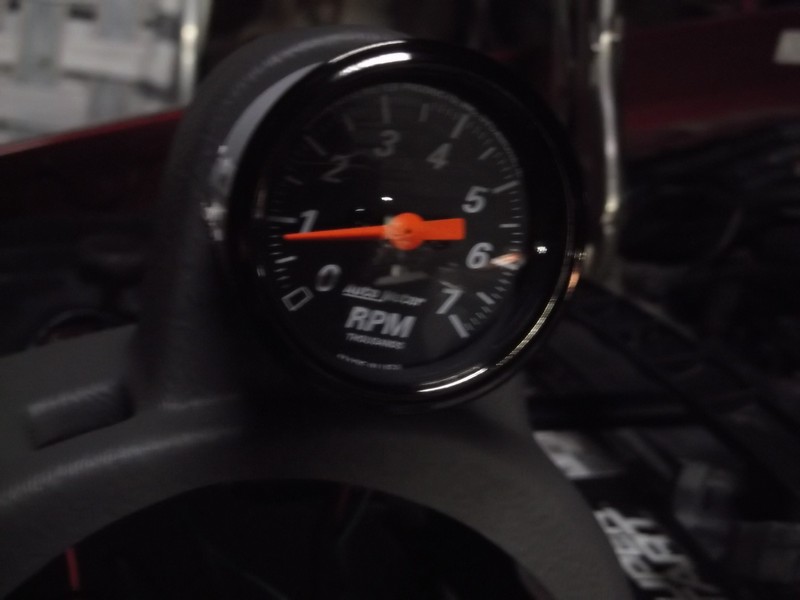 Black tachometer gauge with orange needle showing RPMs.