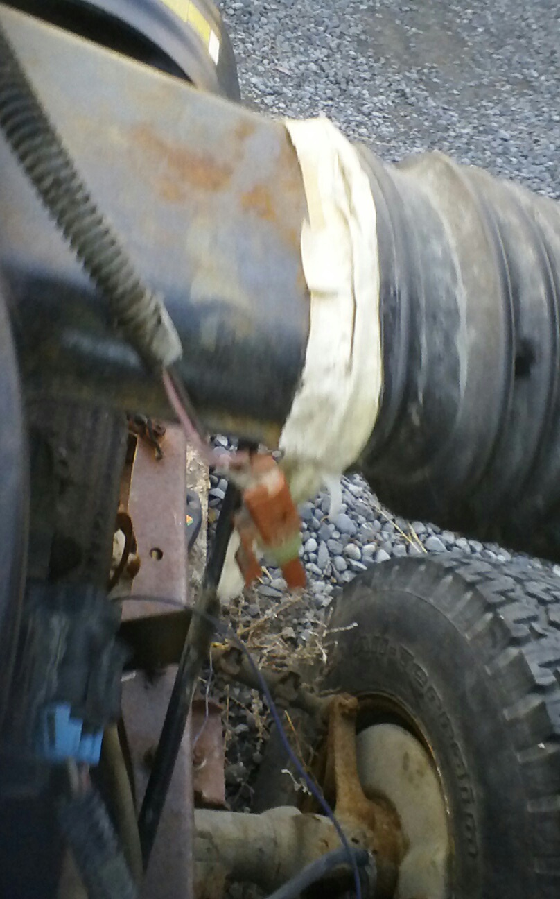 Close-up of a flexible black pipe with white tape on a vehicle, with a tire visible.