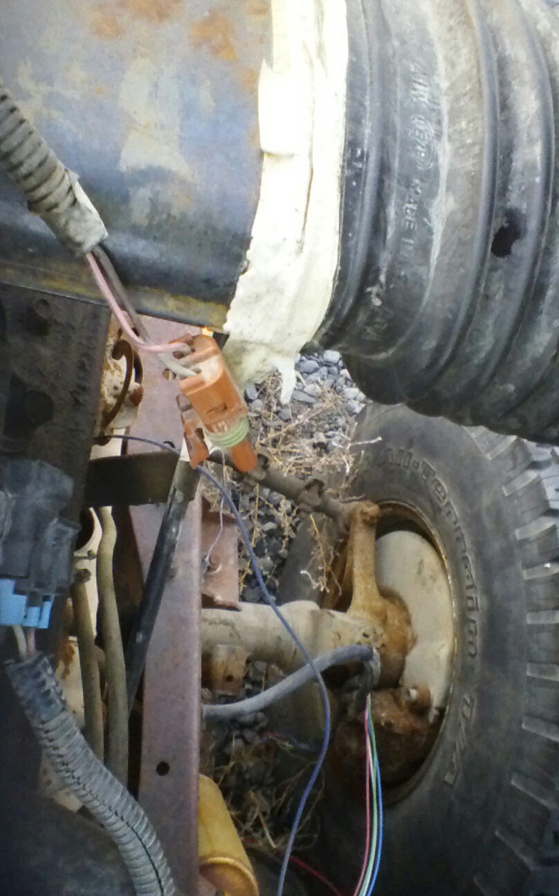 Close-up of vehicle wiring, corrugated pipe, and tire.