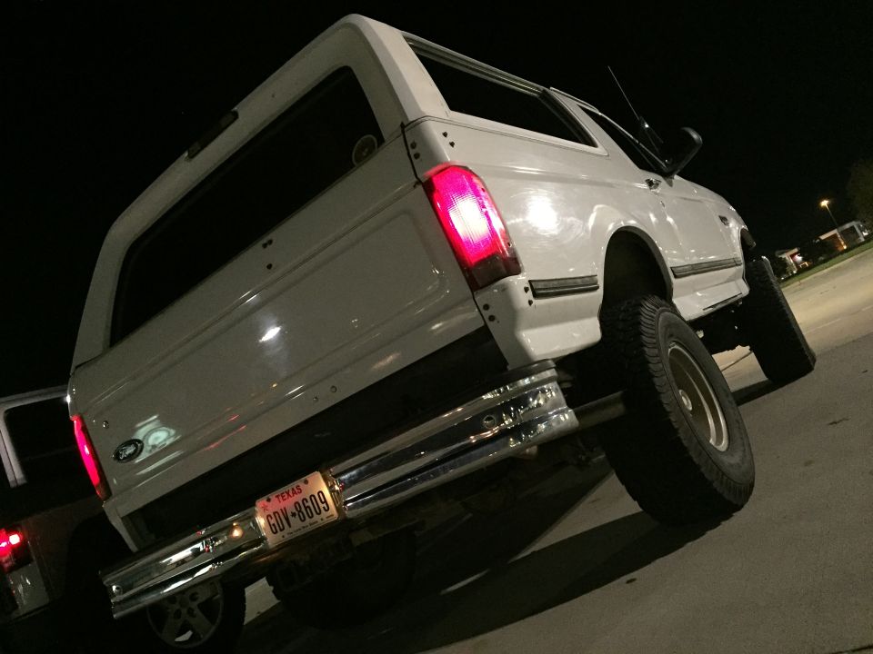 White 1996 Ford Bronco rear passenger side view at night with Texas license plate GDV-8609.