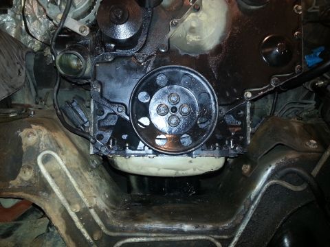 1994 Ford Bronco - The engine bay of a 1994 Ford Bronco shows the front of the engine block, a pulley, and various hoses and wiring. The engine is heavily coa…