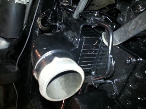 1994 Ford Bronco - A close-up view of a black intake pipe and associated plumbing connected to an engine component. The pipe has a white, ribbed end and is mo…