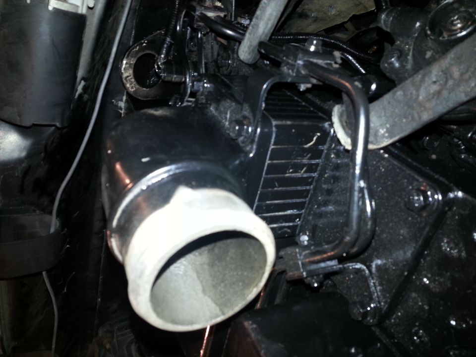 Close-up of black intake pipe with white ribbed end on a vehicle engine.