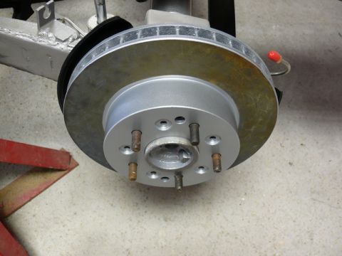 Close-up of a new car brake rotor and hub assembly with lug studs.