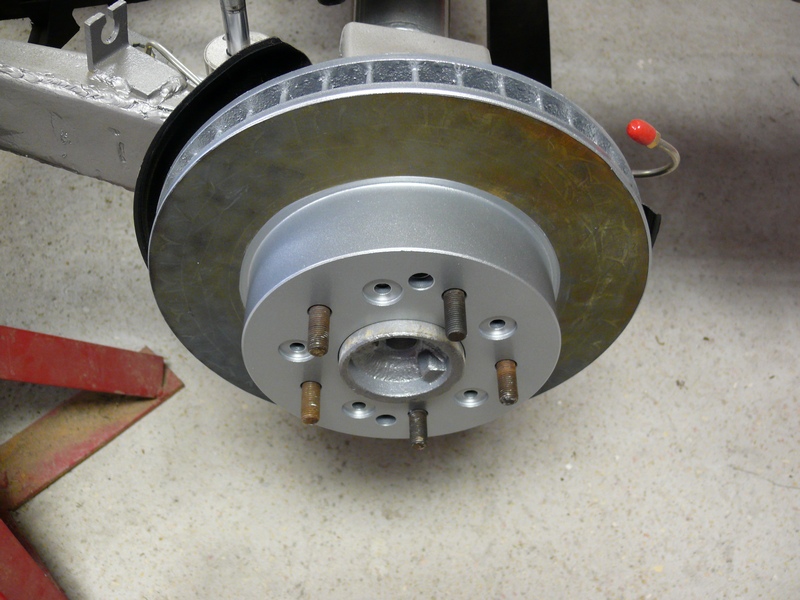 Close-up of a new car brake rotor and hub assembly with lug studs.