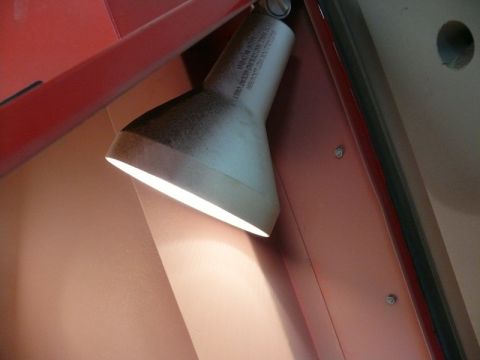 White lamp with black lettering on a red metal surface.