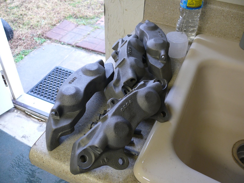 Four gray painted brake calipers on a countertop next to a sink.