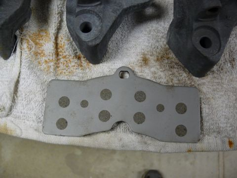 Brake pad with circular cutouts on a towel with brake caliper parts