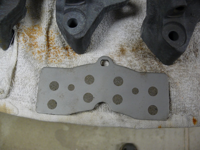 Brake pad with circular cutouts on a towel with brake caliper parts