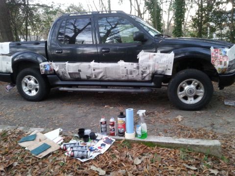 2001 Ford Explorer - A black Ford Explorer Sport Trac pickup truck is parked outdoors with its lower body panels covered in newspaper and tape, suggesting prepa…