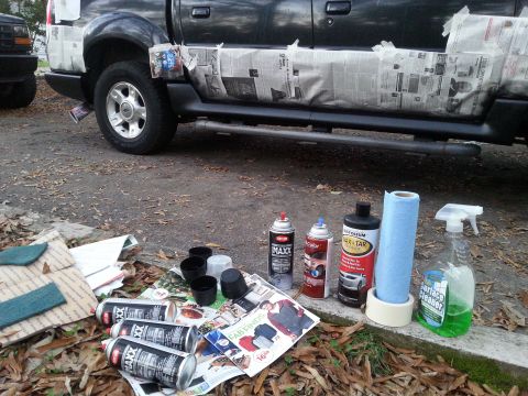 2001 Ford Explorer - A dark-colored pickup truck is parked on a gravel surface with its lower body panels covered in newspaper for protection. Various spray can…
