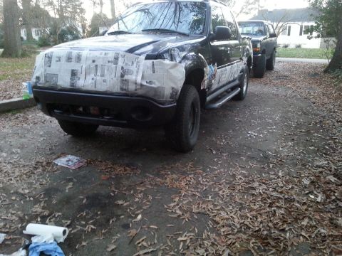 2001 Ford Explorer - The front end of a dark-colored SUV is covered in newspaper and tape, likely for painting. Another dark-colored SUV is parked behind it on…