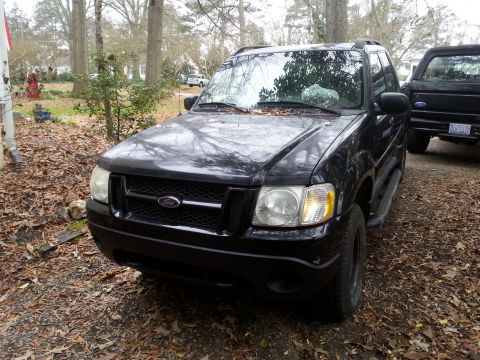 2001 Ford Explorer - A black Ford Explorer is parked on a gravel driveway covered in fallen leaves, with a black pickup truck visible behind it.