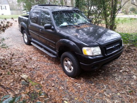 2001 Ford Explorer - A black Ford Explorer Sport Trac is parked on a gravel driveway covered in fallen leaves. The truck is viewed from a 3/4 front angle, showi…