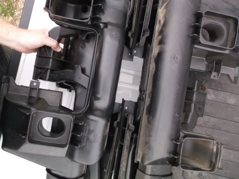 1999 Mercury Grand Marquis - A person's hand is holding a black plastic automotive air intake component. The part appears to be part of a larger assembly with multiple…