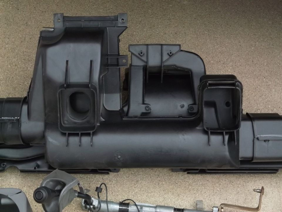 Black plastic air intake manifold system laid out on a textured surface.