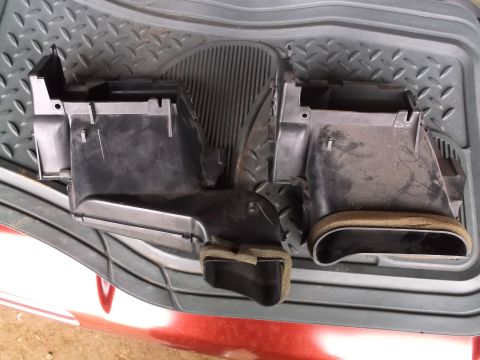 1999 Mercury Grand Marquis - Two black plastic HVAC duct components with foam seals are shown from a top-down perspective, resting on a dark gray textured mat.