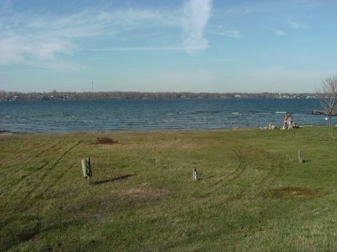 1978 Ford Bronco - A wide view of a lake with a grassy embankment in the foreground and a treeline in the distance.