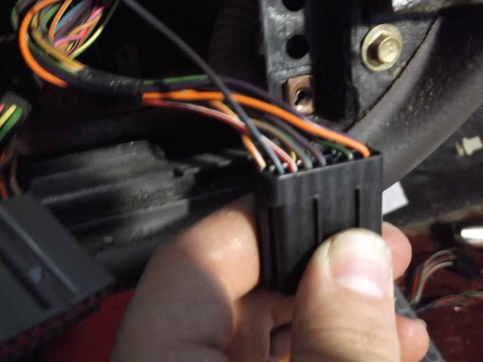 Hand holding a black electrical connector with wires.