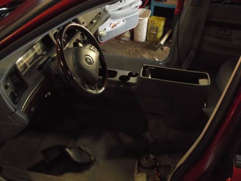 1999 Mercury Grand Marquis - The interior of a red Mercury Grand Marquis is shown, with a focus on the dashboard, steering wheel, and center console. The car appears to…