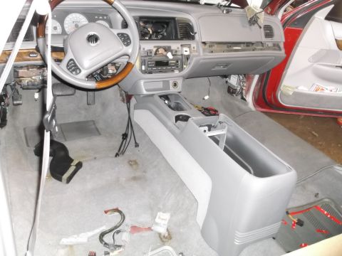 1999 Mercury Grand Marquis - The interior of a car is shown with the dashboard, steering wheel, and center console disassembled. Various wires and parts are scattered o…
