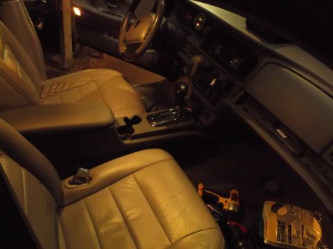 1999 Mercury Grand Marquis - The interior of a car is shown, featuring tan leather seats, a center console with a gear shifter and cup holders, and the dashboard with t…