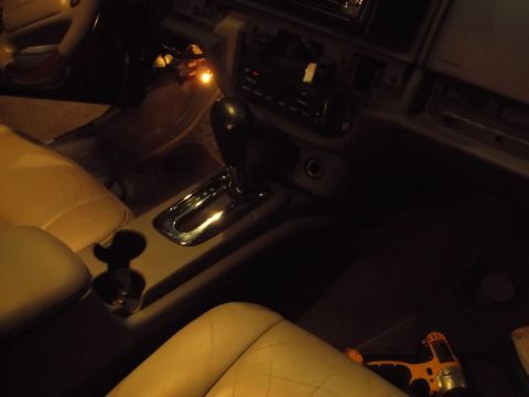 1999 Mercury Grand Marquis - The interior of a car is shown, focusing on the center console and gear shifter. A yellow power drill is visible on the floor in the lower…