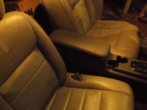 1999 Mercury Grand Marquis - The interior of a car shows tan leather bucket seats with a center console and armrest. The driver's seat has a Lincoln emblem visible on t…