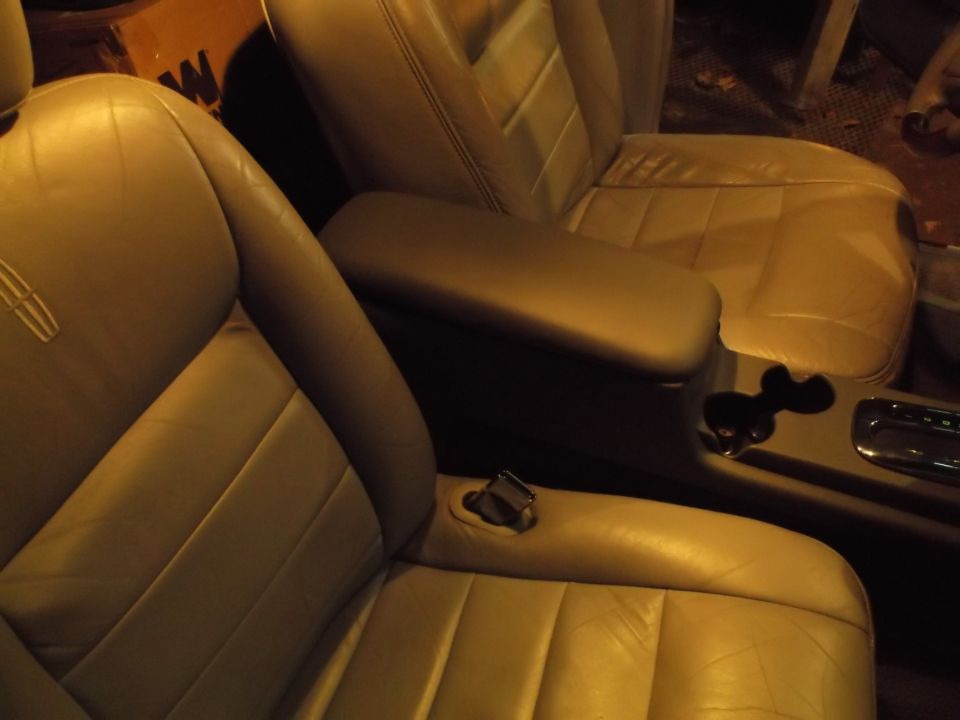 Interior of a car with tan leather bucket seats and a center console.