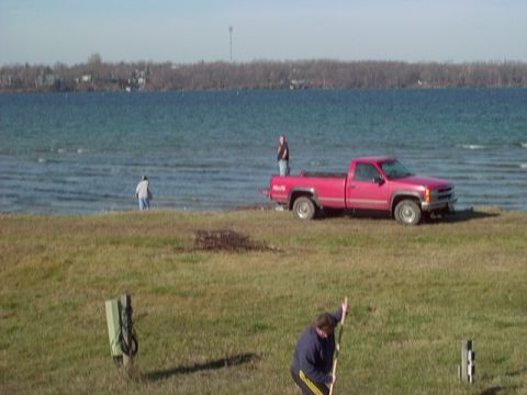 1978 Ford Bronco - Red pickup truck parked by a lake with two people in the background.