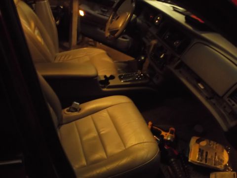 1999 Mercury Grand Marquis - The interior of a car, likely a 1999 Mercury Grand Marquis, is shown from the passenger side. The tan leather seats and dashboard are visib…