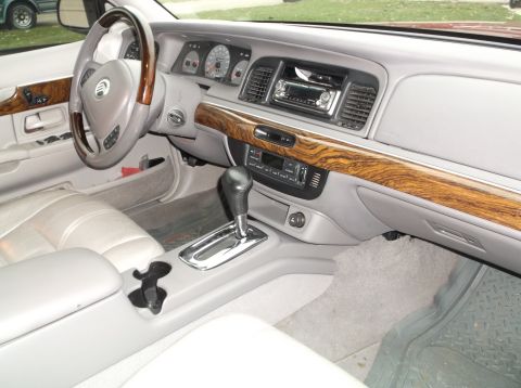 1999 Mercury Grand Marquis - The interior of a 1999 Mercury Grand Marquis shows the dashboard, steering wheel, center console with gear shifter, and passenger seat. The…