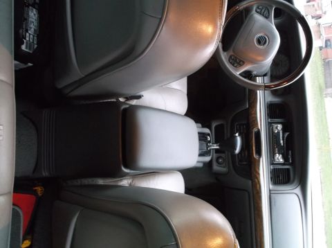 1999 Mercury Grand Marquis - The interior of a car is shown from a high angle, looking down at the center console and dashboard. The vehicle features light-colored leat…