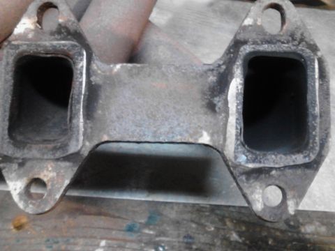 1973 Ford F-250 - This is a close-up shot of a cast iron exhaust manifold with two rectangular ports. The manifold is weathered and shows signs of rust and w…