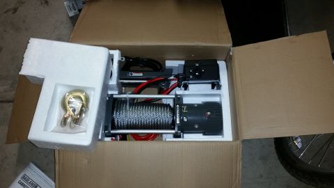 1991 Ford Bronco - A new winch is shown packed in its original cardboard box with foam inserts. A hook is visible in a plastic bag on the left side of the box.