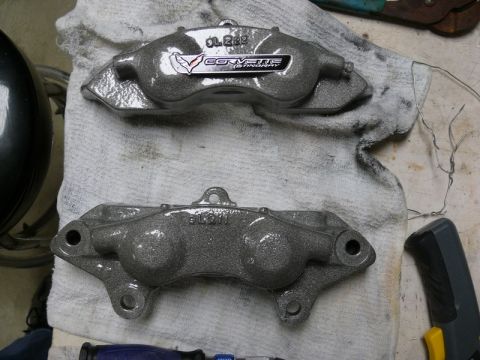 Two gray painted brake calipers, one with a Corvette Stingray logo.