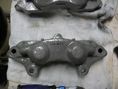 Gray painted brake calipers on a white cloth, one with "BLM" text.
