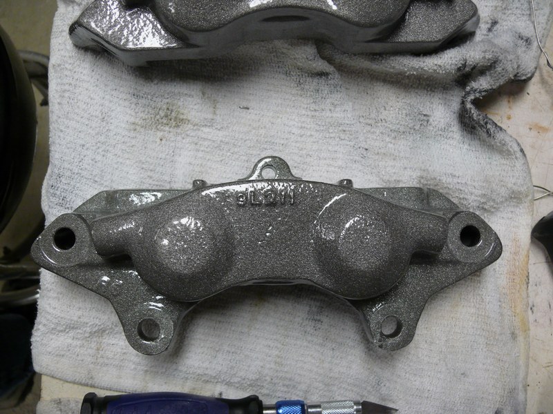 Gray painted brake calipers on a white cloth, one with "BLM" text.