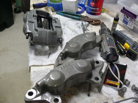 Gray brake calipers on a workbench with tools.