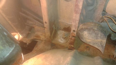 1996 Ford Bronco - This image shows the underside of a vehicle, focusing on rusty metal brackets, a bolt, and a horn. The components appear to be part of the…